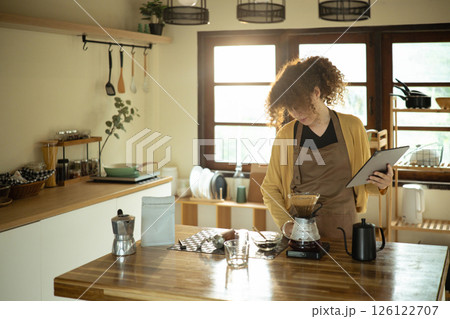 Young woman brewing pour over coffee and using digital tablet in a stylish kitchen 126122707
