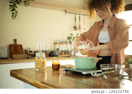 Young woman with curly haired preparing a meal in a bright home Young woman with curly haired preparing a meal in a bright home 126122730