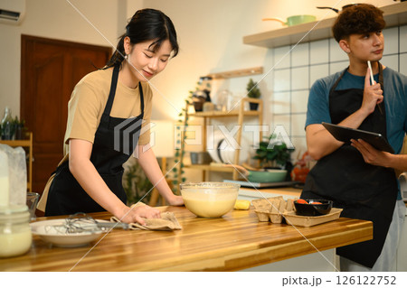 Happy couple preparing pancake batter together in a cozy kitchen 126122752