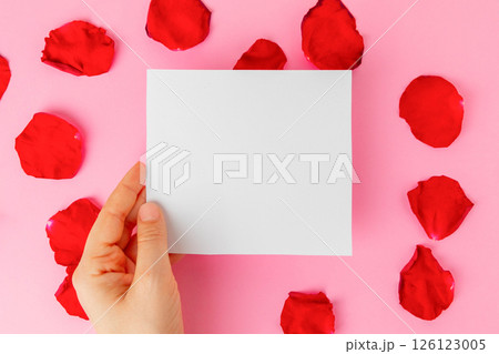 Hand holding a blank paper on romantic pink background 126123005