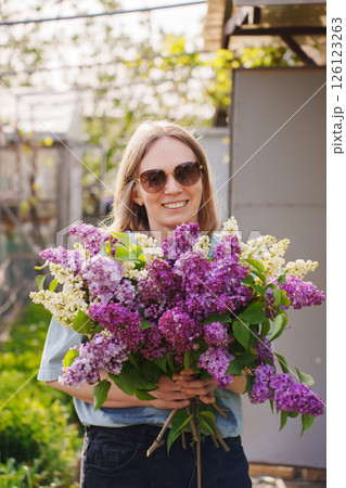 A woman is elegantly holding a beautiful bouquet of purple and white flowers 126123263