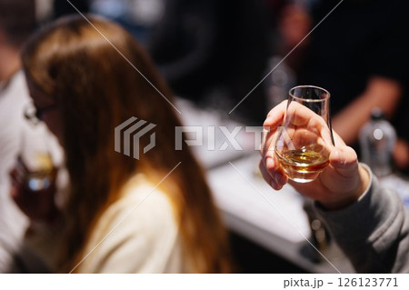 Enjoying whiskey tasting at a cozy bar with friends in the evening Enjoying whiskey tasting at a cozy bar with friends in the evening 126123771