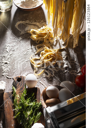 Homemade noodles hanging on wooden dryer rack over messy kitchen table background high angle top view 126123864