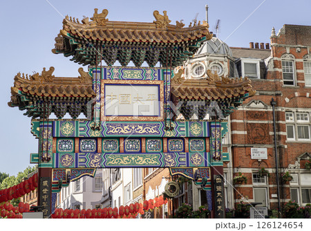 Beautiful view of London Chinatown entrance gate in traditional chinese design with glazed yellow tiles, a golden dragon, painted panels, two white jade plaques and red lanterns. 126124654