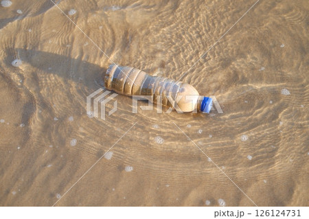 a plastic bottle lying in shallow seawater on a sandy beach a plastic bottle lying in shallow seawater on a sandy beach 126124731