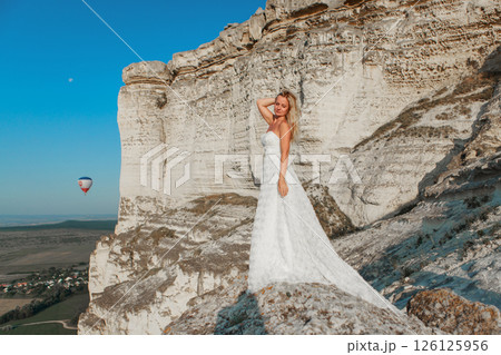 a woman in a white dress, a bride on a mountain with a blue sky. Beautiful nature, freedom, enjoyment of life. High quality photo a woman in a white dress, a bride on a mountain with a blue sky. Beautiful nature, freedom, enjoyment of life. High quality photo 126125956