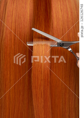 Hairdresser cuts long red hair with scissors 126126748