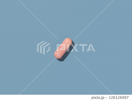 Pink Medical capsule on blue top view, hard shadows. Taking dietary supplements 126126897