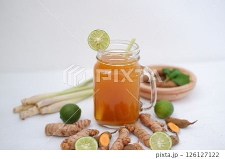 Fresh ginger and lemon juice in a glass jar with ginger roots on white background. Fresh ginger and lemon juice in a glass jar with ginger roots on white background. 126127122