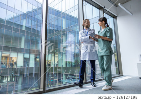 Two doctors discussing an interesting case while walking in the clinic corridor 126127198