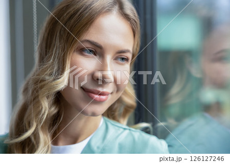 Pretty blonde female doctor in green lab coat near the window in the hospital 126127246