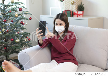 Beautiful Asian woman feel lonely and depressed with smartphone at home during Christmas holiday season. Beautiful Asian woman feel lonely and depressed with smartphone at home during Christmas holiday season. 126127352