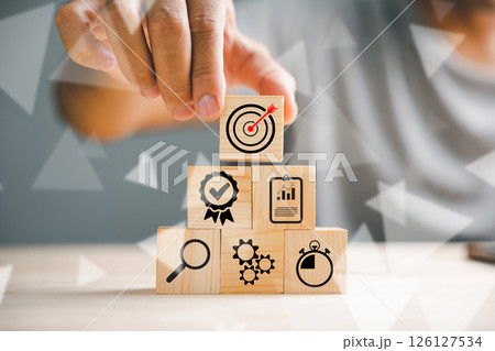 Hand skillfully stacking wood blocks on a table, representing the concept of business strategy and Action plan. Copy space available for professional use. Hand skillfully stacking wood blocks on a table, representing the concept of business strategy and Action plan. Copy space available for professional use. 126127534