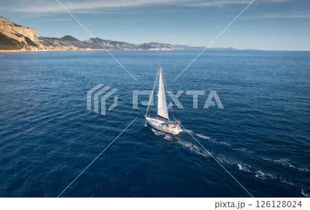 Aerial view of floating sailboat and rocky sea coast at sunny day 126128024
