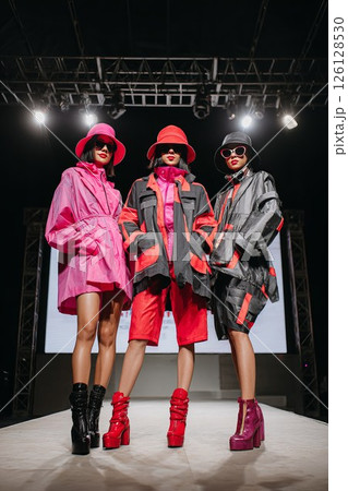 Three models on fashion runway in vibrant outfits, concept of power, unity and style 126128530