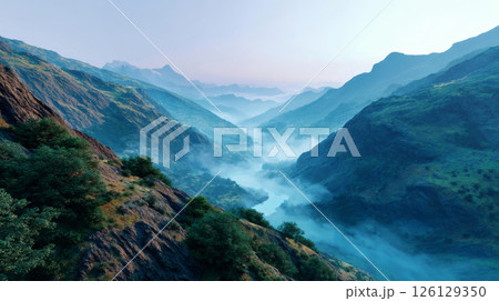 Peaceful panoramic view of mist-covered mountains and river valley under early morning light 126129350