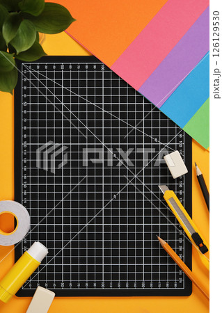 Top view of the paper crafts work table. Craft knife, pencil, eraser, cutting mat, paper. Place for your text. Top view of the paper crafts work table. Craft knife, pencil, eraser, cutting mat, paper. Place for your text. 126129530
