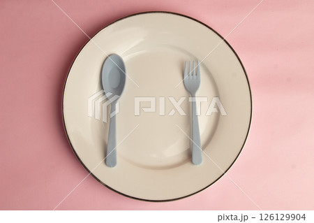 Minimalist Cutlery Arrangement on Pink Canvas, Gray Plastic Spoon and Fork Plate Arrangement, Top View studio shot 126129904