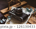 Retro camera on old book and eucalyptus branch on wooden background, flat lay. Vintage style. 126130433