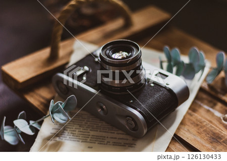 Retro camera on old book and eucalyptus branch on wooden background, flat lay. Vintage style. 126130433