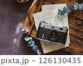 Retro camera on old book and eucalyptus branch on wooden background, flat lay. Vintage style. 126130435