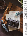 Retro camera on old book and eucalyptus branch on wooden background, flat lay. Vintage style. 126130436