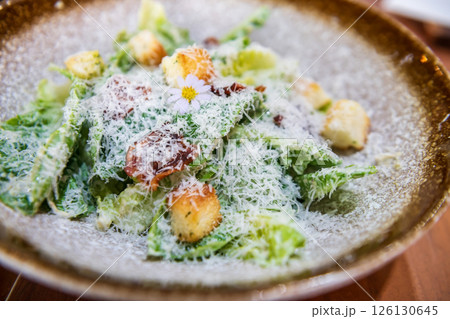 Portion of caesar salad with crispy bacon and bread on plate 126130645