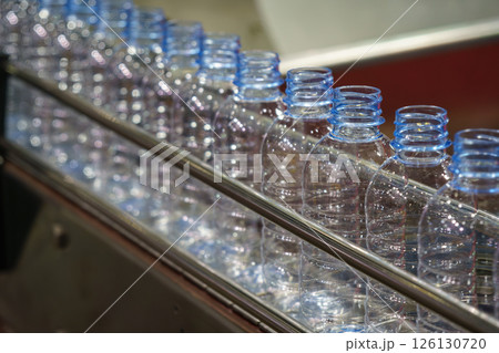 The empty drinking water bottles on the conveyor belt for filling process. The empty drinking water bottles on the conveyor belt for filling process. 126130720