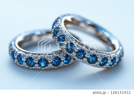 Luxurious pair of wedding rings with blue stones on a white background. Rococo-Renaissance style. 126131412