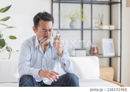 リビングでスマートフォンを使う男性 リビングでスマートフォンを使う男性 126131468