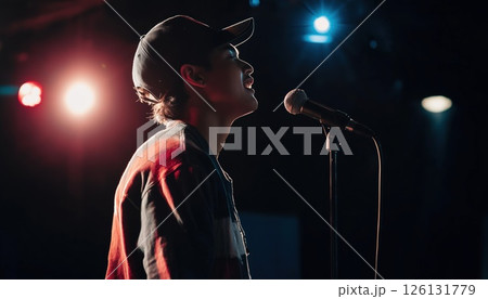 Young Man Entertains Audience With Stand-Up Comedy On Stage, Delivering Jokes Mic In Hand And Singing Songs For Entertainment. 126131779