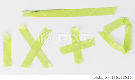 Green tape shapes arranged artistically on white surface in daylight 126132530