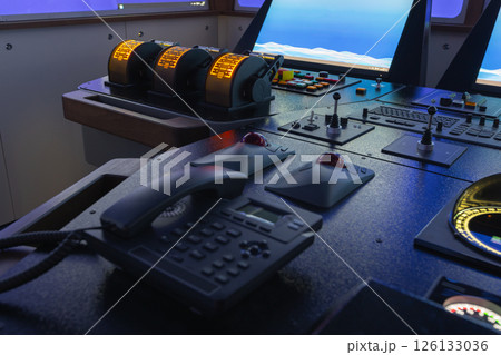 Bridge control panel of a ship featuring throttles, communication devices 126133036