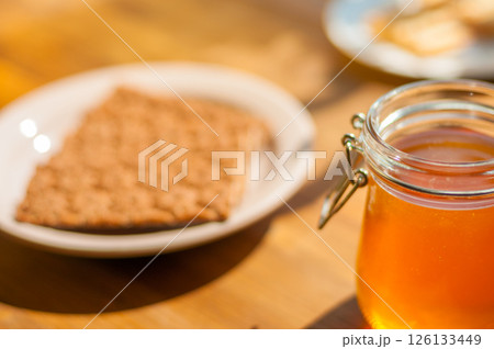 Honey Jar and Gingerbread Cookie on a Table, Warm Sunlight Creates a Cozy Cafe Vibe. Perfect for Bakeries 126133449