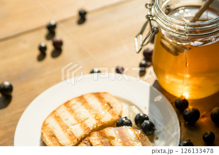 Toasted Bread With Honey and Blueberries, Warm Sunlight, Creating an Inviting Cafe-Inspired Atmosphere Toasted Bread With Honey and Blueberries, Warm Sunlight, Creating an Inviting Cafe-Inspired Atmosphere 126133478