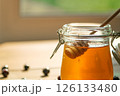 Honey Drips From a Wooden Dipper Into a Glass Jar, Softly Lit ideal for Food Blogs and Wellness Brands 126133480