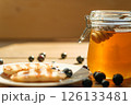 Pancakes Drizzled With Honey Beside a Jar on a Wooden Table, Sunlight Reflecting, Inviting Breakfast Scene for Cafes 126133481