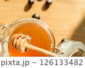 Golden Honey Drips From a Wooden Dipper, Bathed in Warm Sunlight symbolizing Wellness and a Delightful Dining Experience 126133482