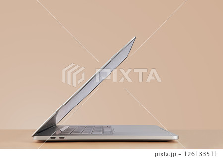 Side view of open laptop on beige background Side view of open laptop on beige background 126133511