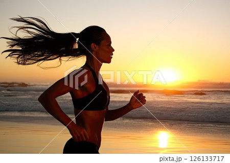 Silhouette of a young woman running on the beach during sunset. A beautiful portrait of a young woman running on the beach, the sunset creating a warm and magical scene. Silhouette of a young woman running on the beach during sunset. A beautiful portrait of a young woman running on the beach, the sunset creating a warm and magical scene. 126133717