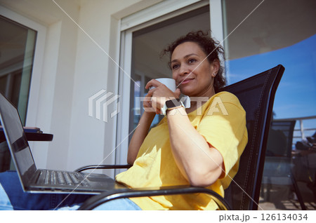 Woman Relaxing Outdoors With Laptop and Coffee in Casual Atmosphere 126134034