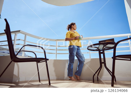 Woman Enjoying a Beverage While Relaxing On a Scenic Modern Balcony Woman Enjoying a Beverage While Relaxing On a Scenic Modern Balcony 126134066