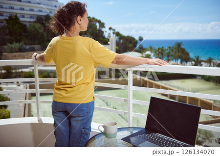 Woman Enjoying Scenic Outdoor View with Laptop on Balcony Woman Enjoying Scenic Outdoor View with Laptop on Balcony 126134070