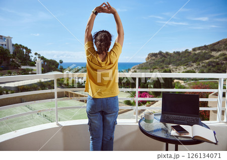 Woman Stretching on a Balcony with Scenic Ocean and Mountain View 126134071