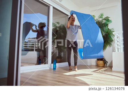 Woman Preparing Yoga Mat at Home in Modern Indoor Setting Woman Preparing Yoga Mat at Home in Modern Indoor Setting 126134076