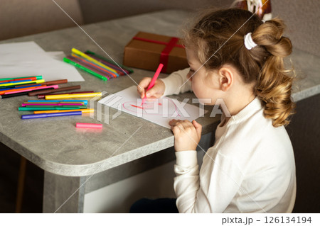 Little girl immersed in drawing process sitting at table in living room. Perfect for child education, parenting and child development concepts. 126134194