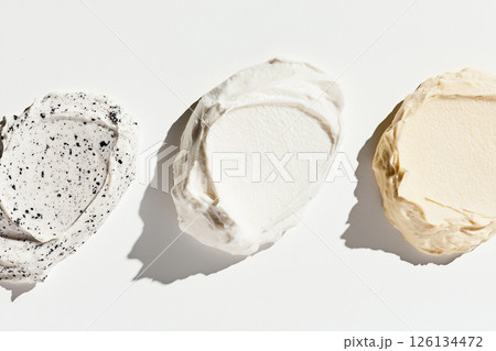 Three textured facial cream swatches in varying shades displayed on a white surface, ideal for representing beauty and skincare products. Three textured facial cream swatches in varying shades displayed on a white surface, ideal for representing beauty and skincare products. 126134472