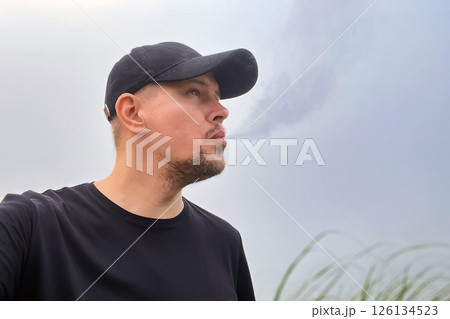 man exhales smoke from vape against fog and smog in nature man exhales smoke from vape against fog and smog in nature 126134523