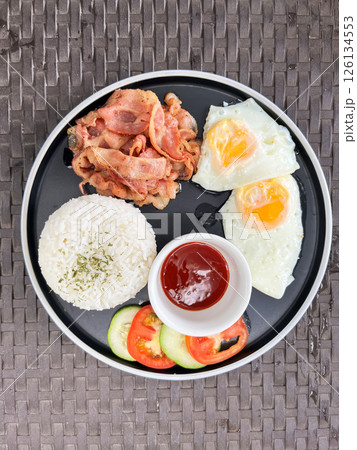 classic breakfast with fried egg, rice and bacon in a cafe 126134553