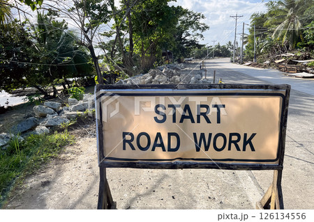road works start sign with dismantled road surface behind, danger on the road road works start sign with dismantled road surface behind, danger on the road 126134556